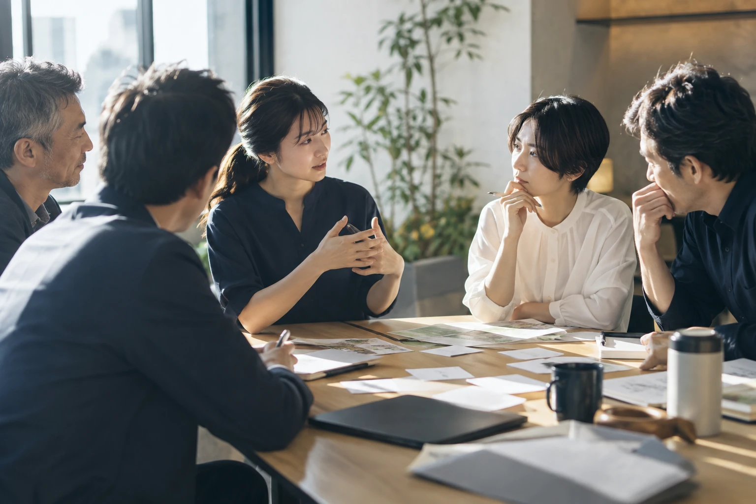 明るい会議室で、世代を越えて真剣に対話し、学び合う企業のチーム